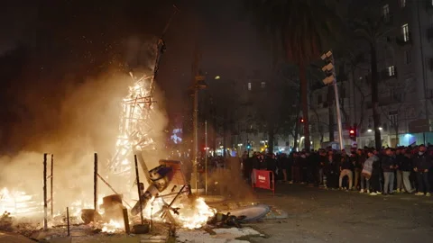 Burning falla wooden frame on Valencia street with spectators during Las Fallas Stock Footage 334302781