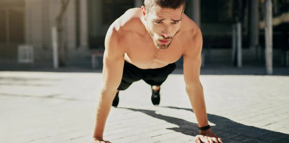 Burning fat and building muscle. a young man doing pushups during his workout in Stock Photos