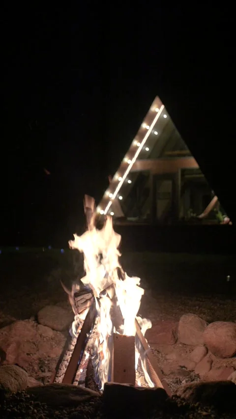 Burning fire against a background of A-frame house located in the forest. 스톡 동영상 311048614