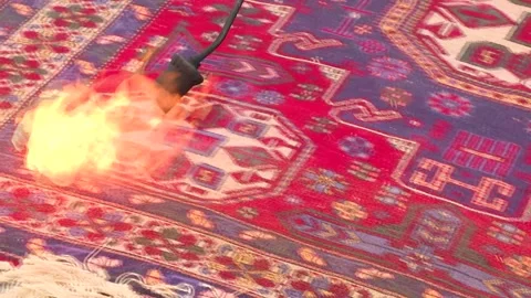 Burning with fire the excess threads left on a newly woven carpet. Video stock 329393165