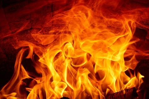 Burning fire flames on a dark background in a wood stove. Stock Photos