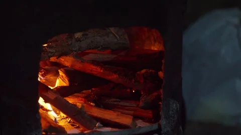 Burning firewood creating glowing embers in dark fireplace Vídeo Stock 345774173