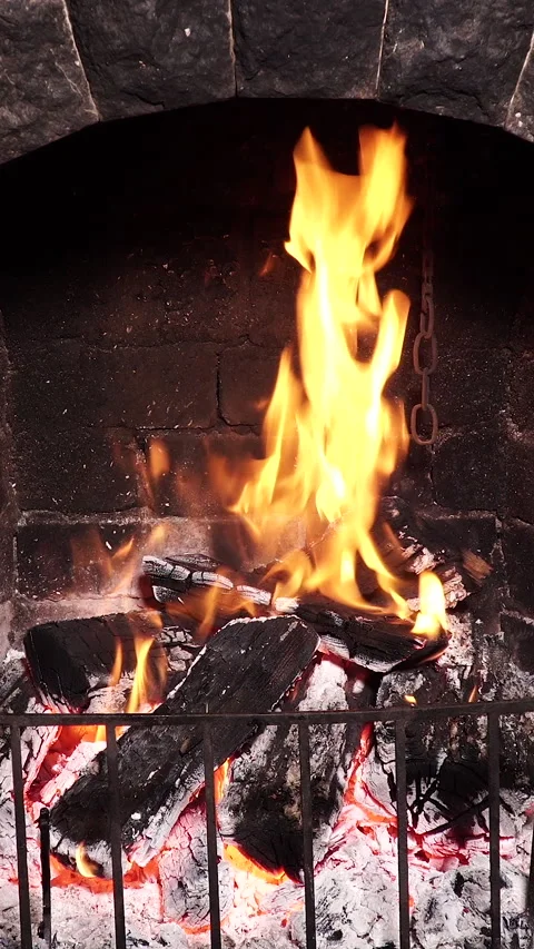 Burning firewood inside stone fireplace creating warm indoor ambiance Vidéo 334385737