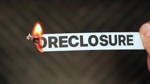 Burning “foreclosure” label held by hand, symbolizing mortgage relief, saving a Stock Footage 333655725