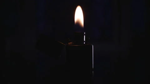 A burning gasoline lighter stands on a table not against a dark background Video stock 153116989
