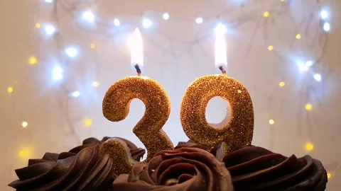 Burning gold candles in the shape of the number 39 on a birthday cake Stock Footage 105447532