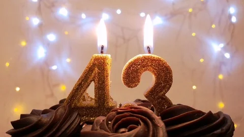 Burning gold candles in the shape of the number 43 on a birthday cake Stock Footage 105447535