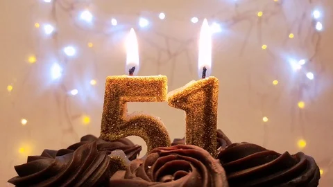 Burning gold candles in the shape of the number 51 on a birthday cake Stock Footage 105447622