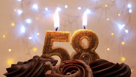 Burning gold candles in the shape of the number 58 on a birthday cake Stock Footage 105447675