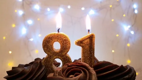 Burning gold candles in the shape of the number 81 on a birthday cake Stock Footage 105448809