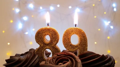 Burning gold candles in the shape of the number 89 on a birthday cake Stock Footage 105448901