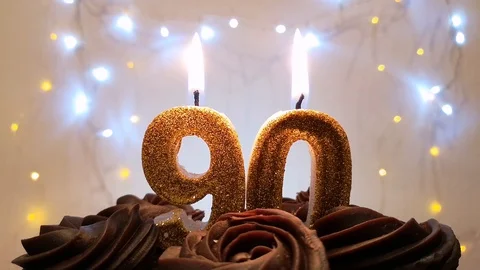 Burning gold candles in the shape of the number 90 on a birthday cake Stock Footage 105448902