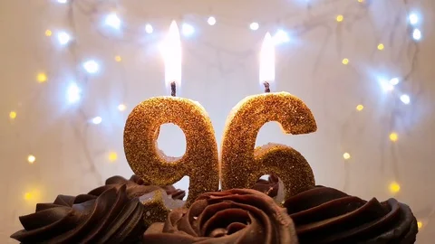Burning gold candles in the shape of the number 96 on a birthday cake Stock Footage 105448928