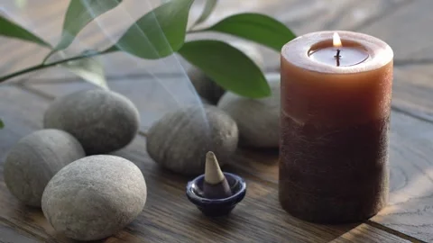 Burning incense cone with aromatic smoke, burning candel and pebble stones Stock Footage 247580983