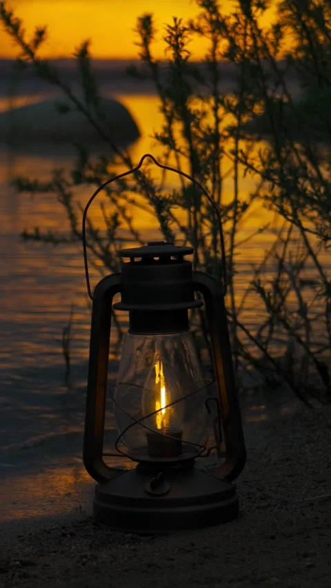 A burning lantern at dusk on the shore of a lake at sunset. Stock Footage 336620899