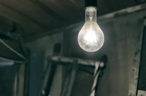 Burning light bulb in an old barn Stock Photos