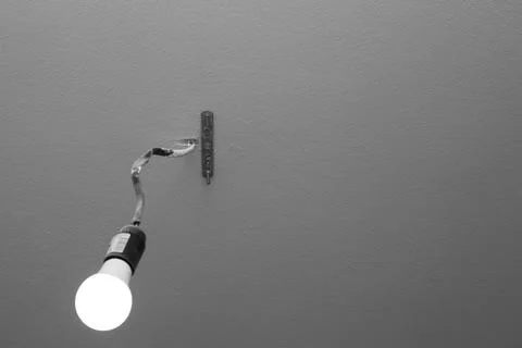 Burning light bulb on a wire on the ceiling. Room lighting, installation and  Stock Photos