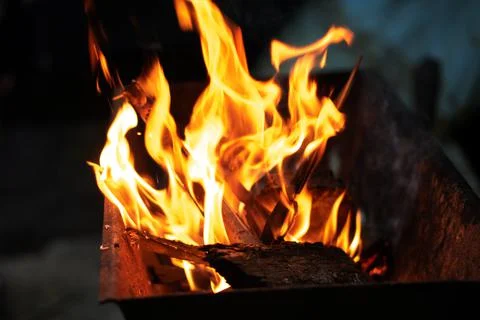 Burning logs in the grill on a dark background Stock Photos