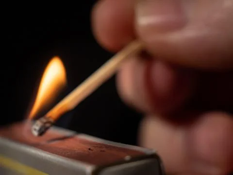 Burning match on a black background. Flame from a lit match. Stock Photos
