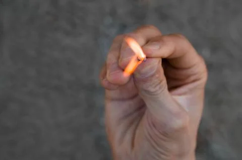 Burning match in hand. Stock Photos