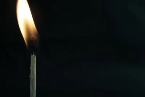 Burning match in the left corner of the frame on a black background Foto stock