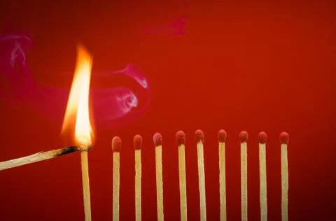 Burning matchsticks setting fire to its neighbors Stock Photos