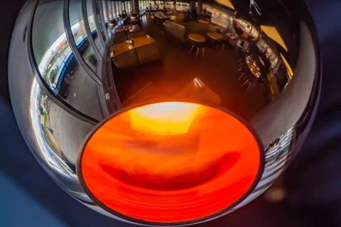 A burning mirror spherical lamp with a reflection of a cafe is on a blue and Stock Photos