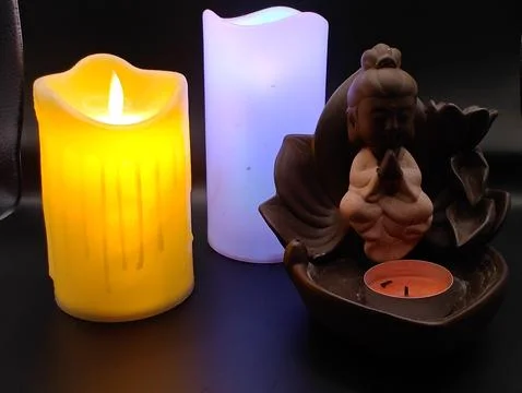 Burning multi-colored candles and a spa figurine Stock Photos