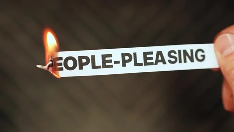 Burning “people-pleasing” label held by hand, symbolizing setting boundaries Stock Footage 333649913