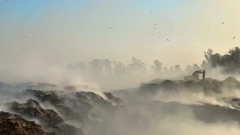 Burning pile of garbage at dump ground or landfill Excavator segregating garbage Stock Footage 160664184