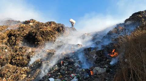 Burning pile of garbage at dump ground. Sanitation Workers segregating garbage Stock-Fotos