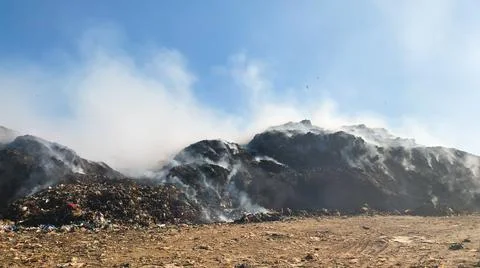 Burning pile of garbage at dump ground or landfill releasing toxic smoke Stock-Fotos