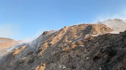Burning pile of garbage at dump ground or landfill releasing toxic smoke Stock-Fotos