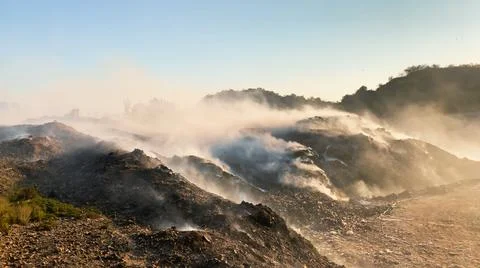 Burning pile of garbage at dump ground or landfill releasing toxic smoke 스톡 사진