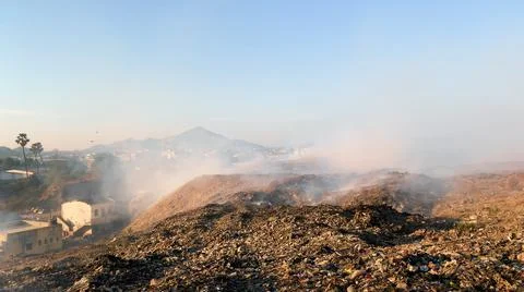 Burning pile of garbage at dump ground or landfill releasing toxic smoke Stock-Fotos
