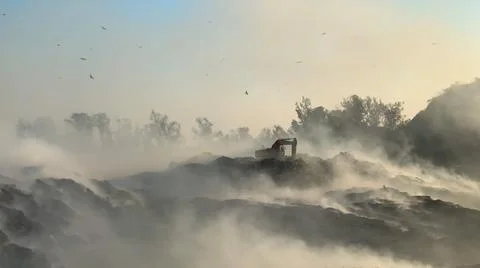 Burning pile of garbage at dump ground or landfill Excavator segregating garbage 스톡 사진