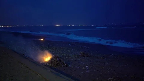 A burning pile of trash on the beach at night Video stock 74295032
