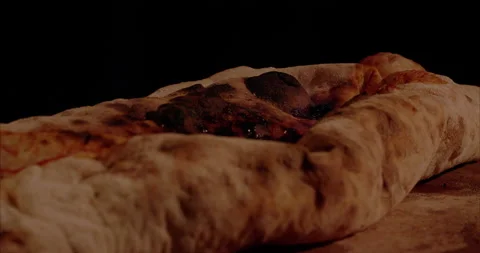 Burning Pizza, Rolled Calzone Rotating Closeup, Black Background Stock Footage 130953357