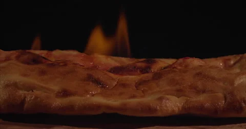 Burning Pizza, Rolled Calzone Rotating Closeup, Black Background Video stock 130954556