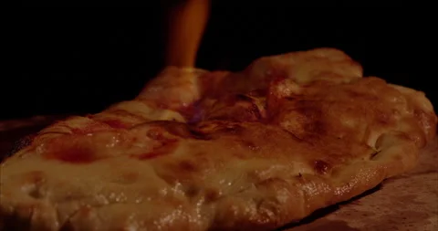 Burning Pizza, Rolled Calzone Rotating Closeup, Black Background Stock Footage 130955432