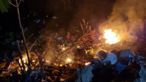 Burning plastic and paper waste on the ground with fire smoke Stock Footage 277936150