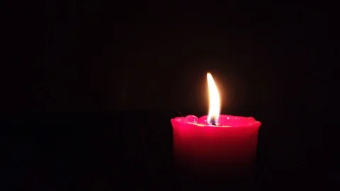 Burning red candle with flickering flame on dark background. Stock Footage 105261293