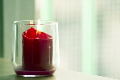 Burning red candle inside a clear glass vase Foto stock
