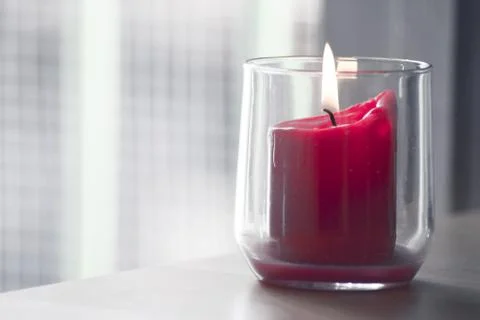 Burning red candle inside a clear glass vase Stock Photos