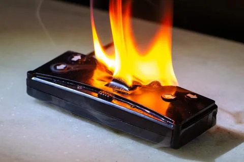 Burning remote control device with fire and sparks as fire threat and damage  Foto stock