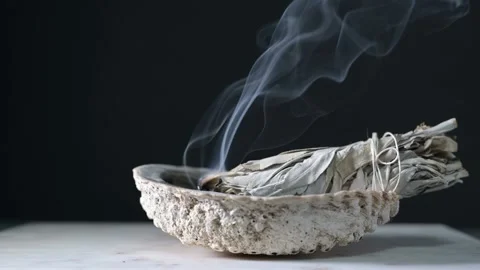Burning sage in a shell on a wood table with black background showing sage Stock Footage 219445048