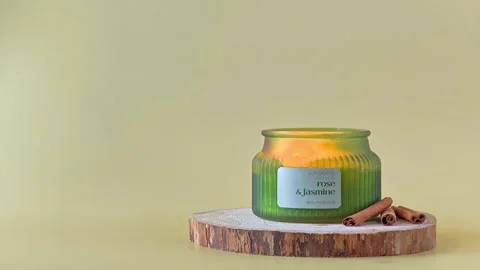 Burning scented candle with a flickering flame inside a green ribbed jar. Stock Footage 338026926