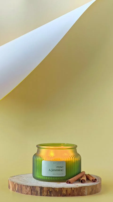 Burning scented candle with a flickering flame inside a green ribbed jar. Stock Footage 338026971