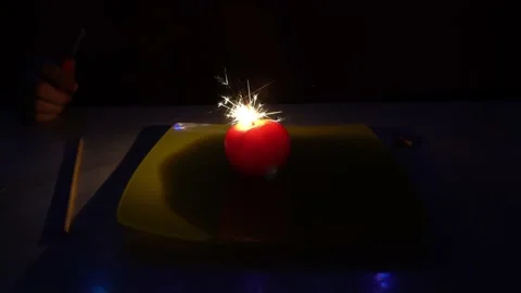A burning sparkler inside a glowing tomato. Video stock 237740473