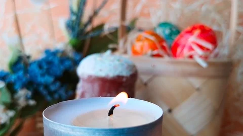 Burning tea light candle. Easter cake, basket with Easter eggs and flowers Stock Footage 104654345